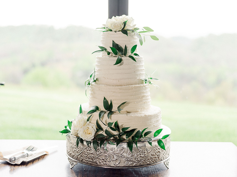 A beautiful four-tier wedding cake with greenery decor.